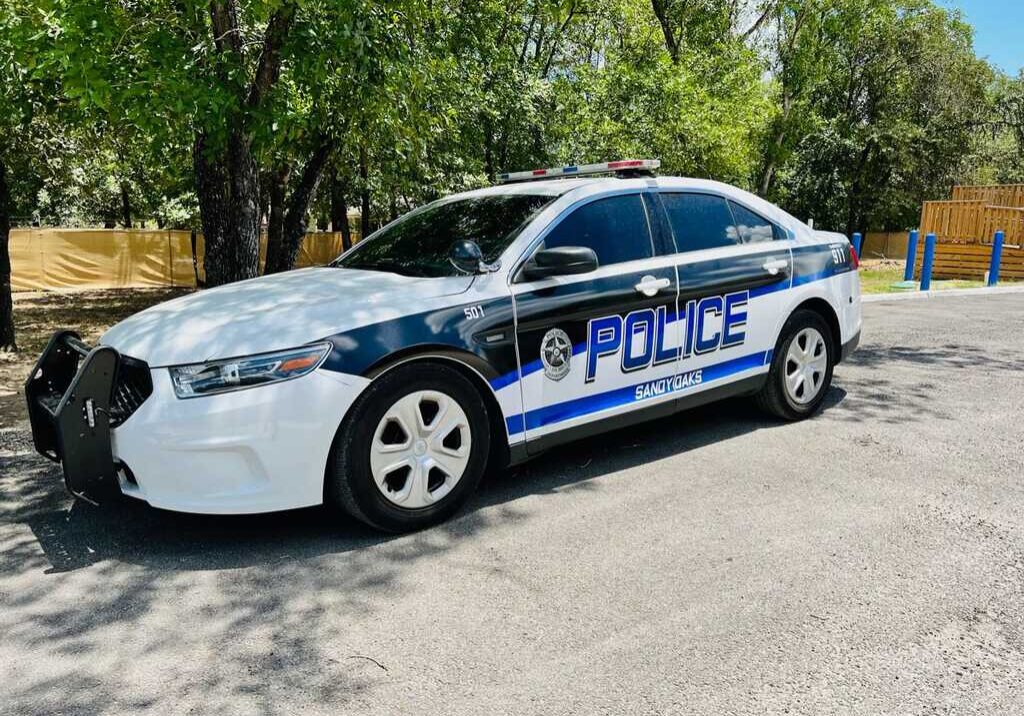 A white police car parked on a sunny street.